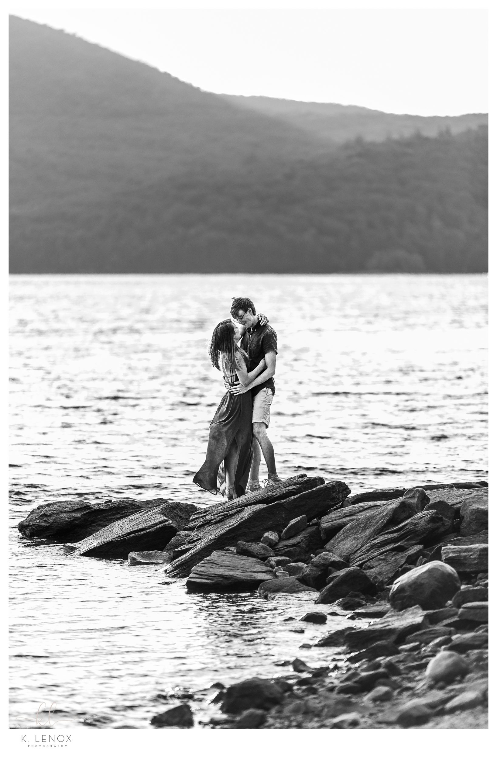 Black and White image of a man and woman standing on the rocky shore of the Harriman Reservoir in Wilmington VT at their Engagement Session