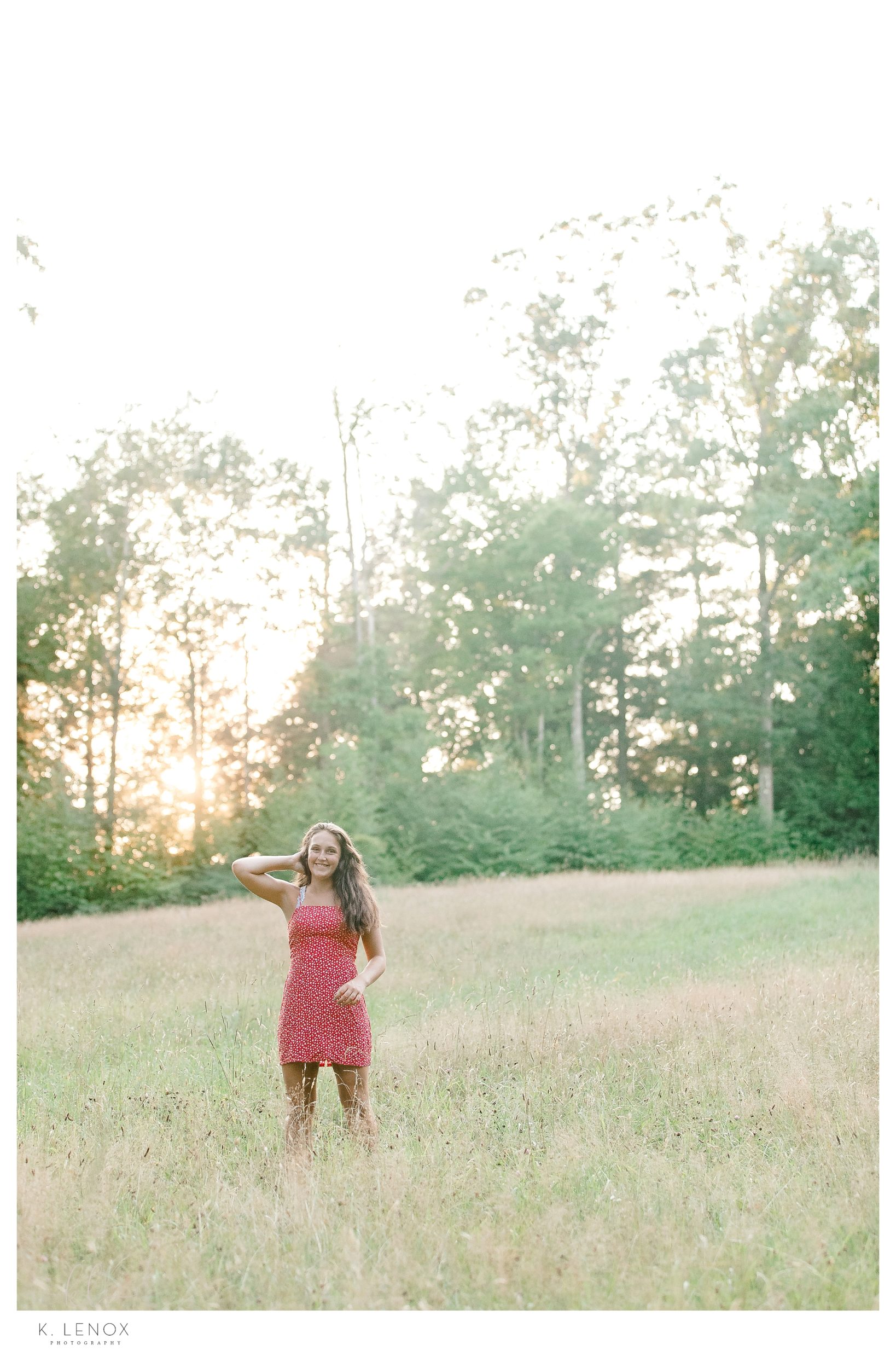Summer Senior Photos In Keene- Girl in a field at sunset wearing a red dress. 