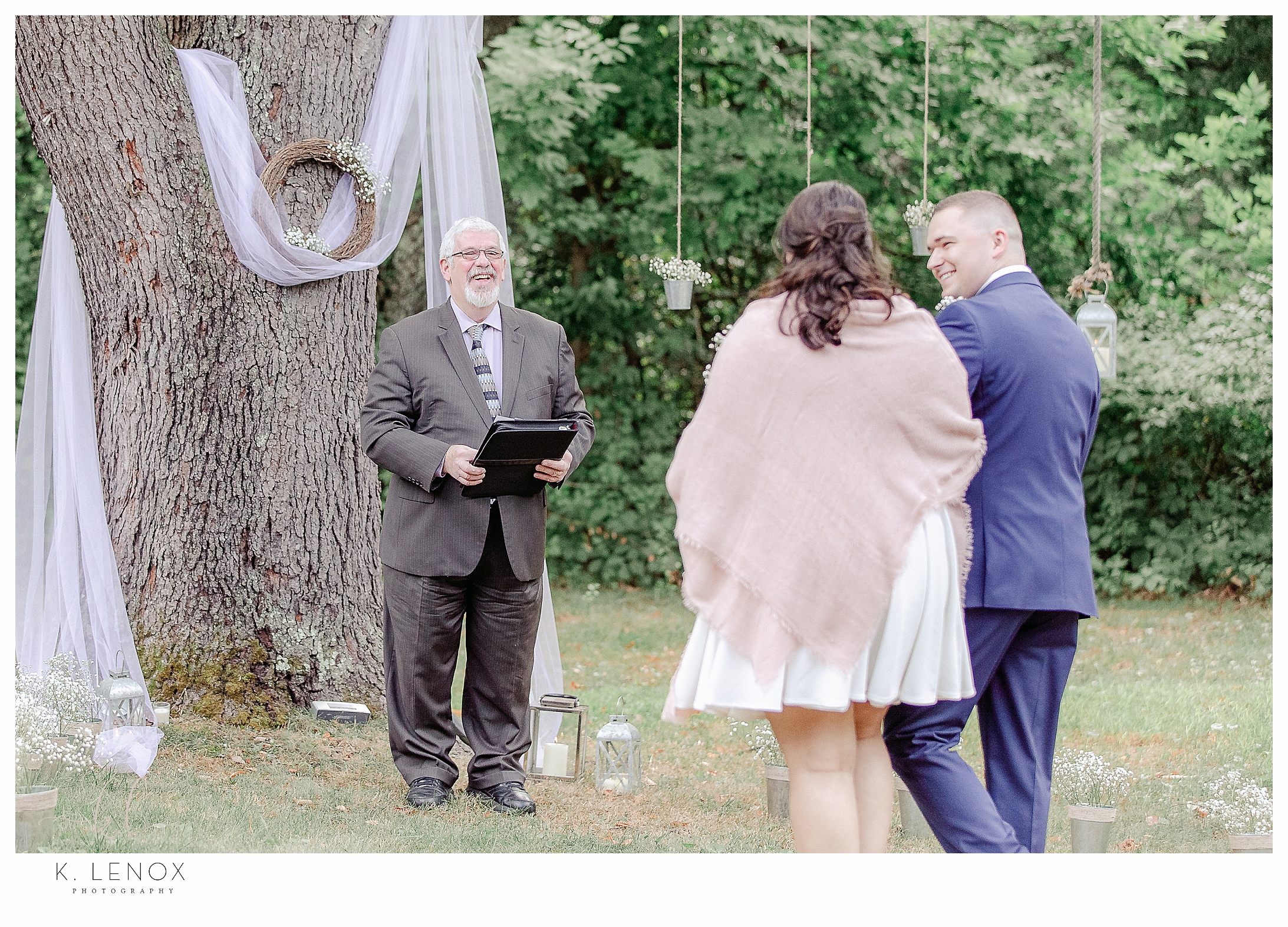 Light and Airy Backyard Elopement showing the officiant smiling as the couple walk towards him. 