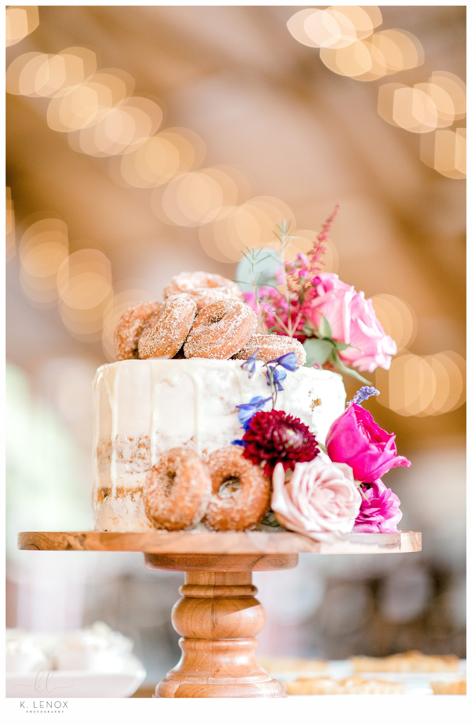 Tiered Wedding Cake decorated with flowers and Donuts. 