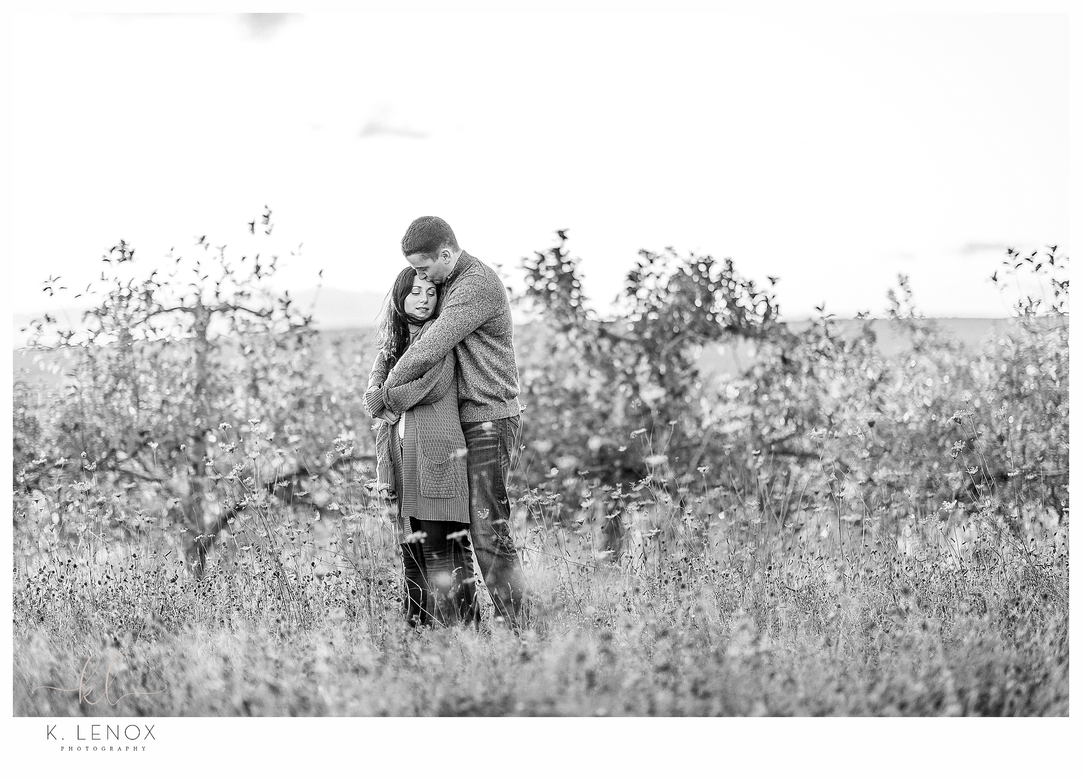 Fun and Carefree Engagement Session in NH- Black and White image of a man and woman hugging in a field. 