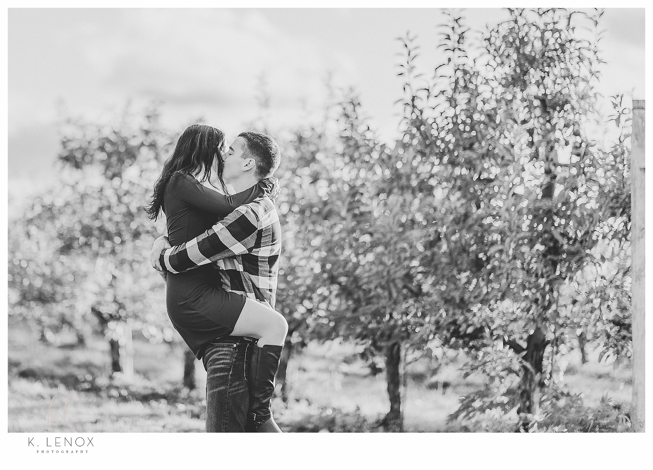 Fun and Carefree Engagement Session in NH- Black and White photo of a man and woman in an orchard, hugging. 