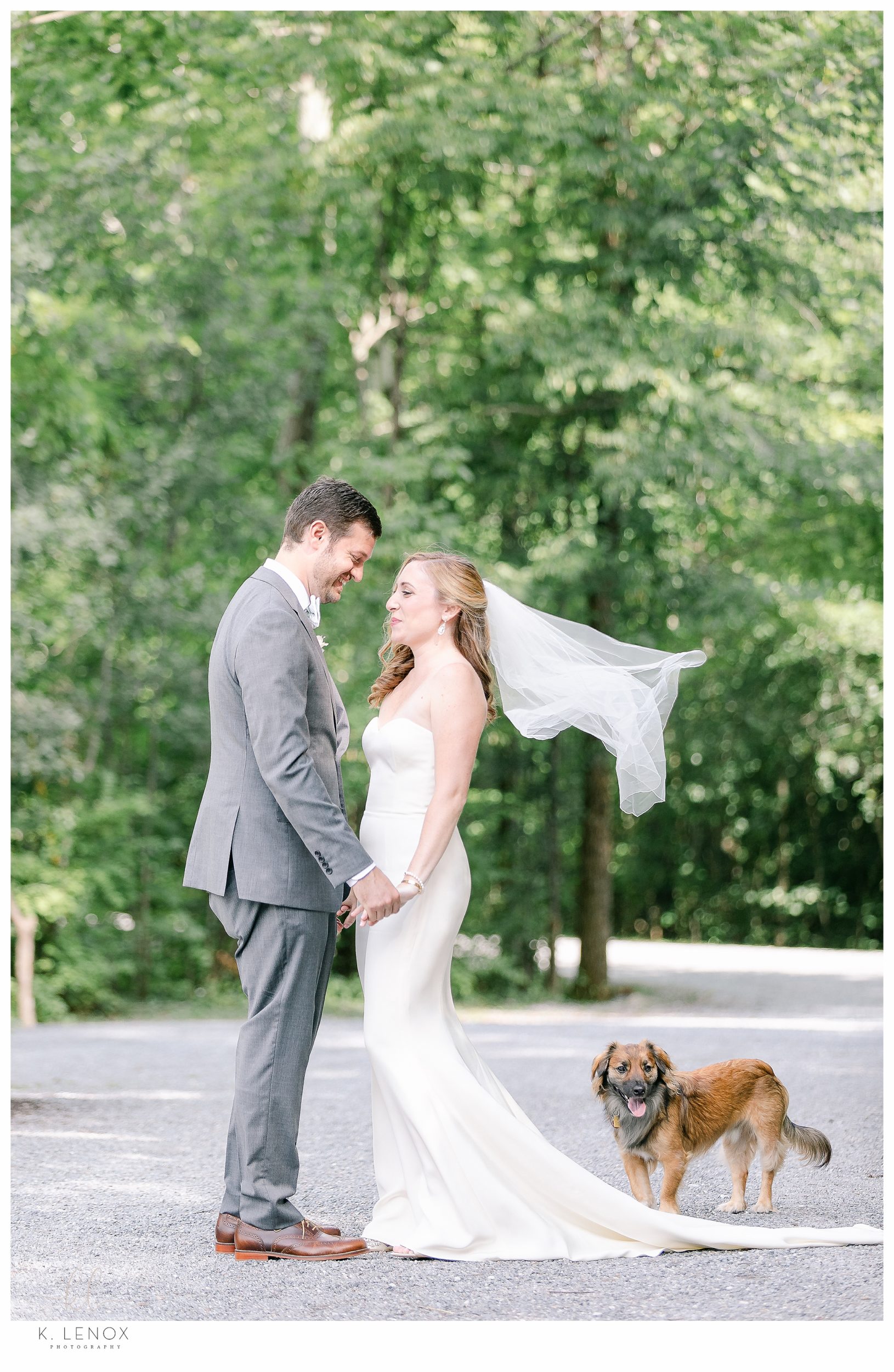 Bride and Groom stand hand in hand for a portrait on their Wedding day at the Equinox Resort, while their dog stands near. 