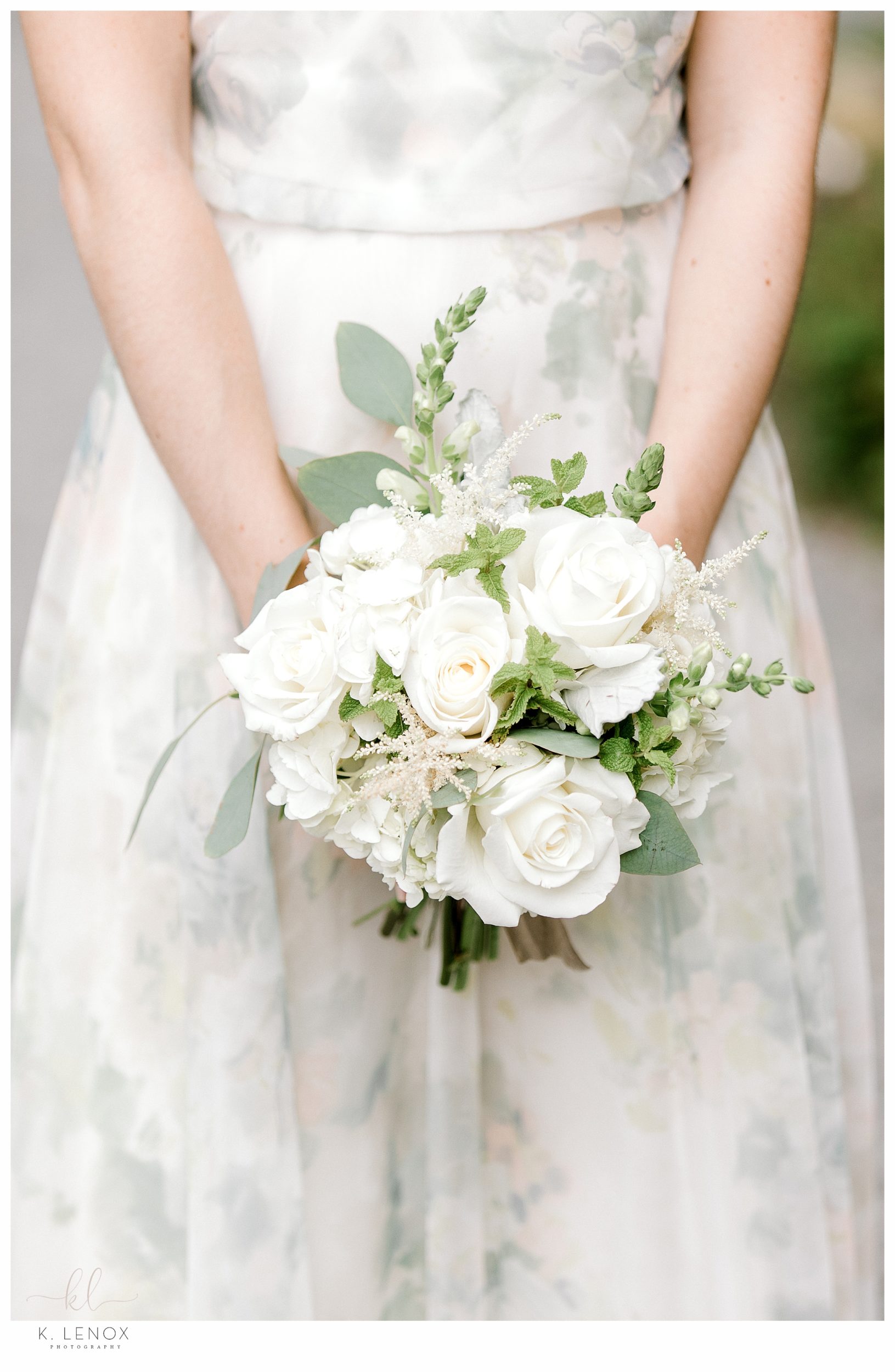 Closeup detail photo of a bridesmaids bouquet showing various white flowers and greenery. 